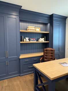 an office with blue painted cabinets and a brown leather chair in front of the desk