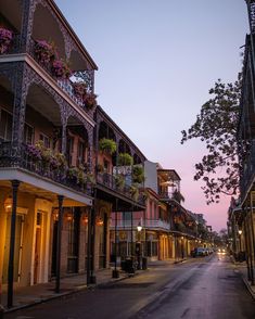 an empty city street at dusk with flowers on the balconies and balconyes