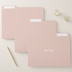 three pink file folders sitting on top of a desk next to a pen and pencil