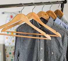 clothes hanging on wooden hangers in a closet