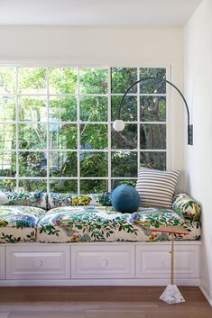 a window seat in the corner of a living room with pillows and throw pillows on it