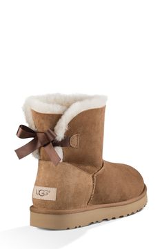 A satin bow adorns the back of a supremely cozy boot made from plush genuine shearling. Pretreated to repel water and stains, the boot also features a Treadlite by UGG™ sole for added cushioning, traction and durability. 1 1/4" heel 1" platform (size 9) 6 1/2" shaft Pull-on style Water-repellent Leather upper/genuine-shearling lining/synthetic sole Shearling may be sourced from Australia, Ireland, the UK, or the USA. See packaging for confirmed country of origin Imported Ugg Mini Bailey Bow, Cute Uggs, Ugg Mini Bailey, Ugg Ankle Boots, Uggs With Bows, Mini Baileys, Pretty Shoes Sneakers, Cozy Boots, Bailey Bow Uggs