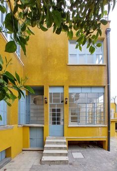 a yellow building with steps leading up to the front door and second story window area