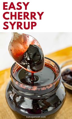 an easy cherry syrup recipe in a glass jar with a spoon pouring it into the jar