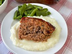 meatloaf, mashed potatoes and green beans on a white plate with red checkered tablecloth