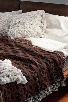 an unmade bed with white and brown blankets on top of it, next to a wooden headboard