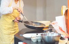 a woman in an apron is frying some food