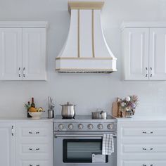 a stove top oven sitting inside of a kitchen next to white cupboards and drawers