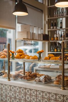 an assortment of baked goods on display in a bakery window with hanging lights above them