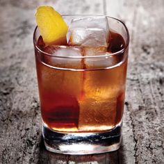 a close up of a drink in a glass with ice and a lemon wedge on the rim