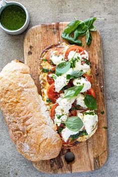 an open face sandwich on a wooden cutting board next to a bowl of pesto