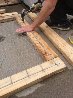 a man is working on some kind of construction project with wooden planks and wire