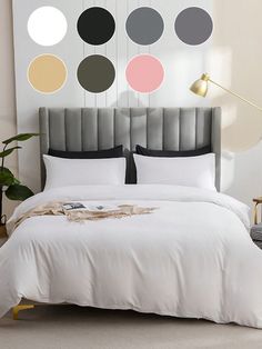 a bed with white sheets and pillows in front of a wall mounted art piece that has circles on it