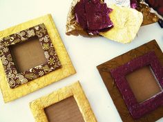 three different colored frames sitting on top of a white table next to some brown paper