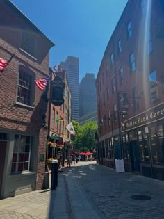 the sun shines brightly on an old brick street in boston, massachusetts as people walk down it