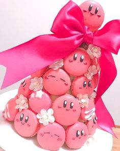 a tower of cookies with faces on them and a pink ribbon tied around the top