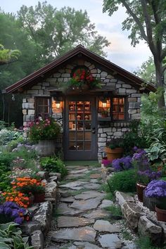 a small stone house surrounded by flowers and trees