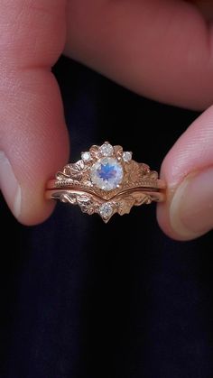 a person holding a gold ring with a blue and white stone in it's center