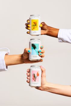 three women holding up cans of tea in the air with their hands on top of each other