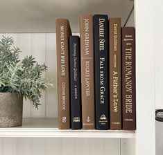 three books are sitting on a shelf next to a potted plant