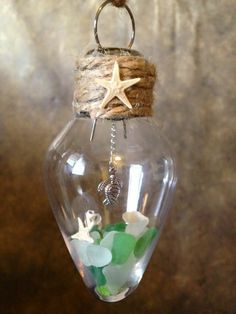 a glass ornament hanging from a rope with sea glass and starfish in it