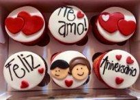 four cupcakes in a box with hearts and the words feliz amo