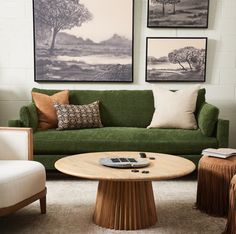 a living room with green couches and pictures on the wall above them, including a coffee table