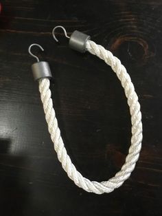 a close up of a white rope on a table with two hooks attached to it