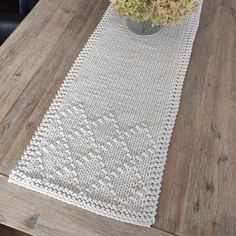 a white table runner on top of a wooden table with a vase filled with flowers