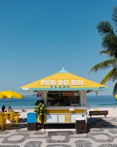 a yellow and white food stand sitting on top of a sandy beach