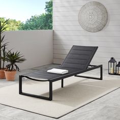 a lounge chair sitting on top of a white rug next to a potted plant