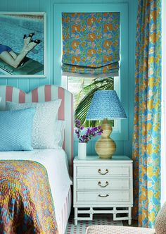 a bedroom with blue walls and colorful curtains