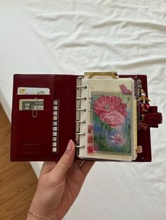 a hand holding an open notebook with flowers on it and a notepad attached to the cover