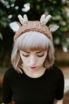 a woman with blonde hair wearing a knitted deer headband and looking down at her cell phone