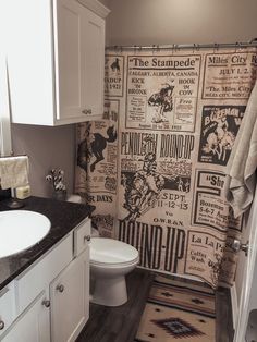 a bathroom with a toilet, sink and shower curtain covered in newspaper paper on the wall