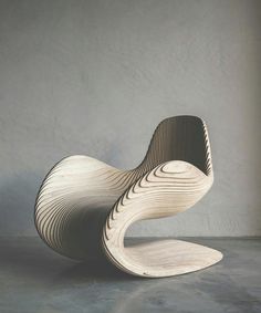 a wooden chair sitting on top of a cement floor next to a white wall in a room