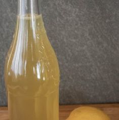 a glass bottle filled with liquid next to two lemons