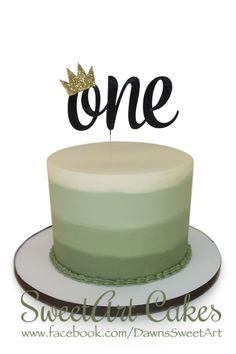 a cake with the word one on top and a single candle sticking out of it