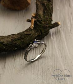 a silver ring sitting on top of a wooden table next to a piece of wood