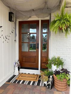 a front door with two potted plants and a welcome mat