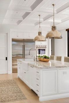 a large kitchen with an island in the middle and two pendant lights hanging from the ceiling