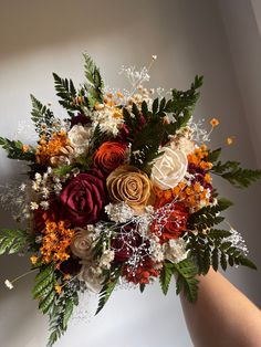 a person holding a bouquet of flowers in their hand with the background white and orange