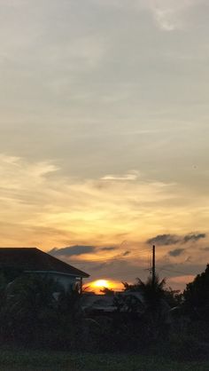 the sun is setting over some houses and trees