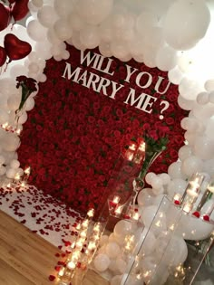 balloons and flowers are arranged in front of a wall that says will you marry me?