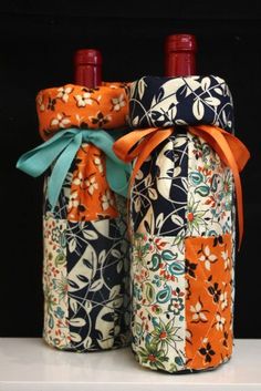 two wine bottles wrapped in fabric with bows