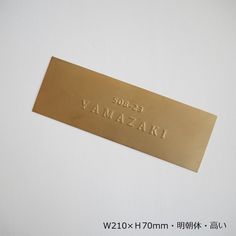 a gold metal name plate on a white surface with writing in english and chinese characters