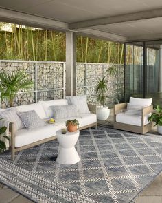 an outdoor living area with couches and potted plants