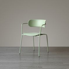 a green chair sitting on top of a hard wood floor next to a white wall