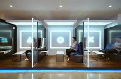 two people sitting on chairs in a room with glass partitions to divide them from each other