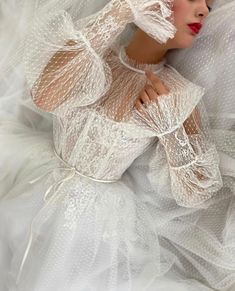 a woman laying on top of a bed wearing a white dress and headpieces